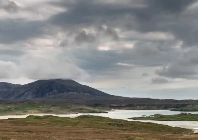 Uig Bay, white beaches and rugged mountains beneath dramatic storm clouds on the Isle of Lewis, Scotland.