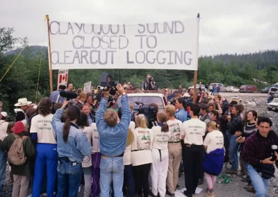 Protesters and journalists gathered beneath a banner opposing clearcut logging in Clayoquot Sound, photographed by Garth Lenz.