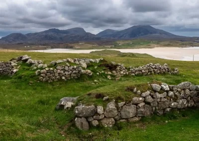 Old stone croft walls overlooking Uig Bay and its rugged mountains on the Isle of Lewis, Scotland.