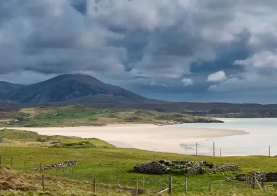 Sweeping view across the white sands of Uig Bay towards mountains and scattered croft houses on Lewis.